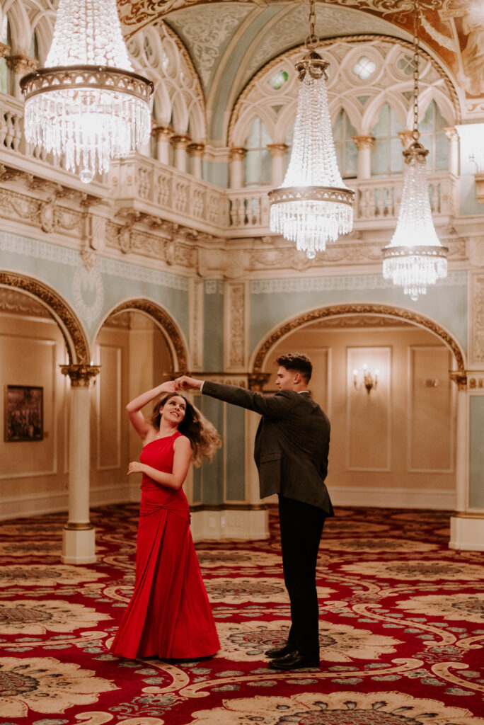 couple slow dancing under chandelier in hall of doges at davenport hotel