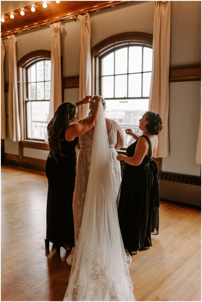 bridesmaids helping bride with vail for wedding