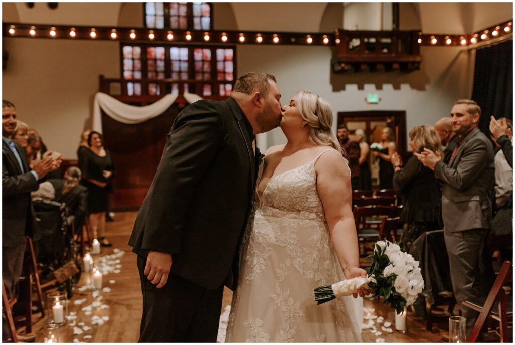 bride and groom kiss in aisle after wedding ceremony