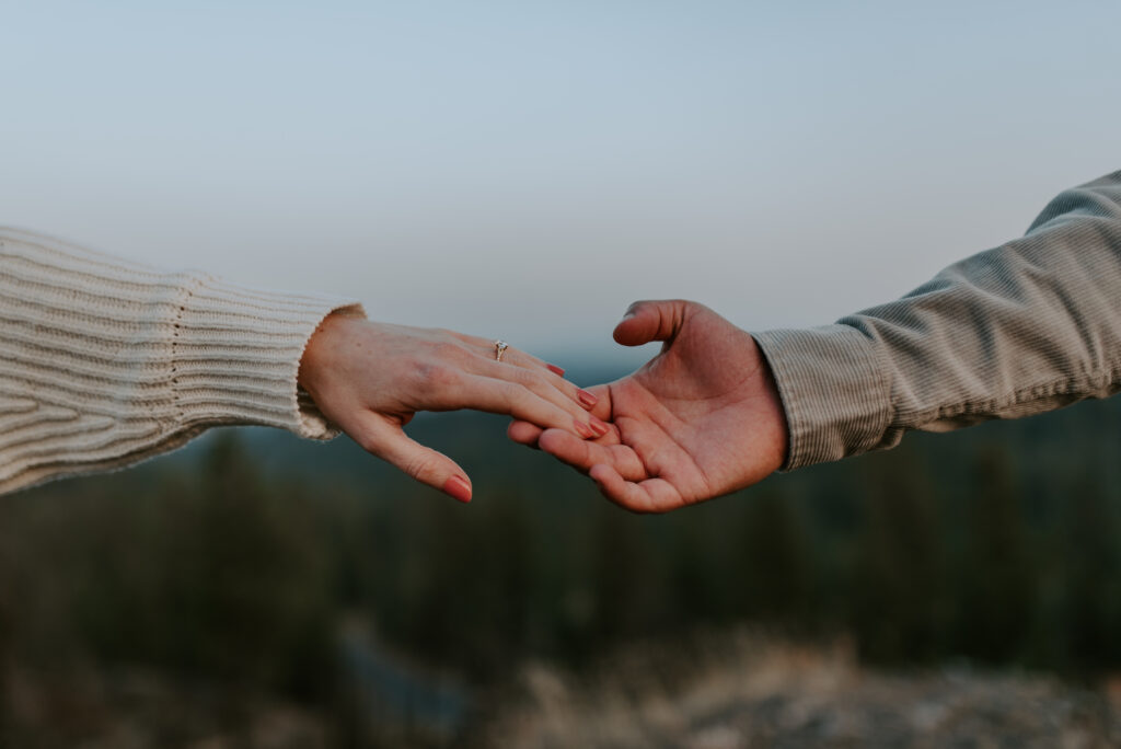 engaged couple holding hands on a mountain in Spokane Washington