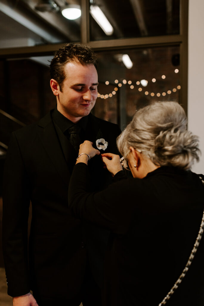 Groom getting his boutonniere put on on his wedding day 