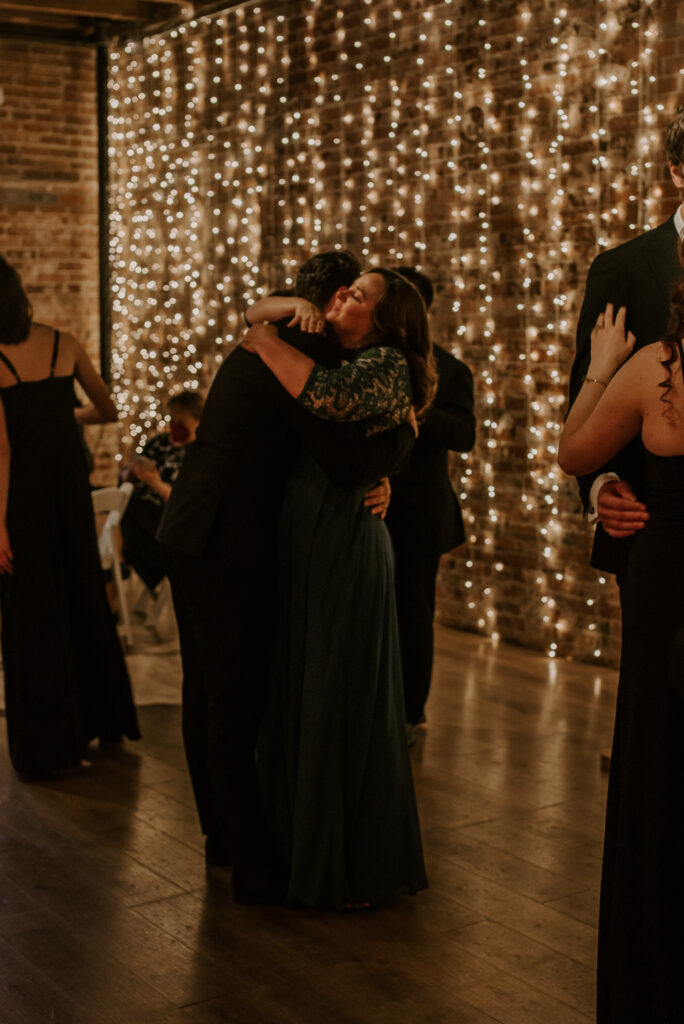 Mother and groom hug after mother/son dance with wedding party