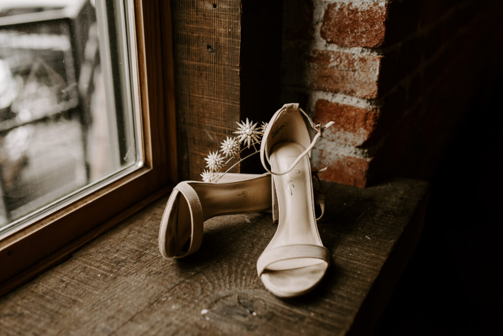 Bride's shoes and headpiece sitting in front of a window. 