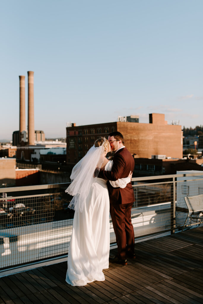 bride and groom duing golden hour on montvale event center rooftop with a view of Spokane