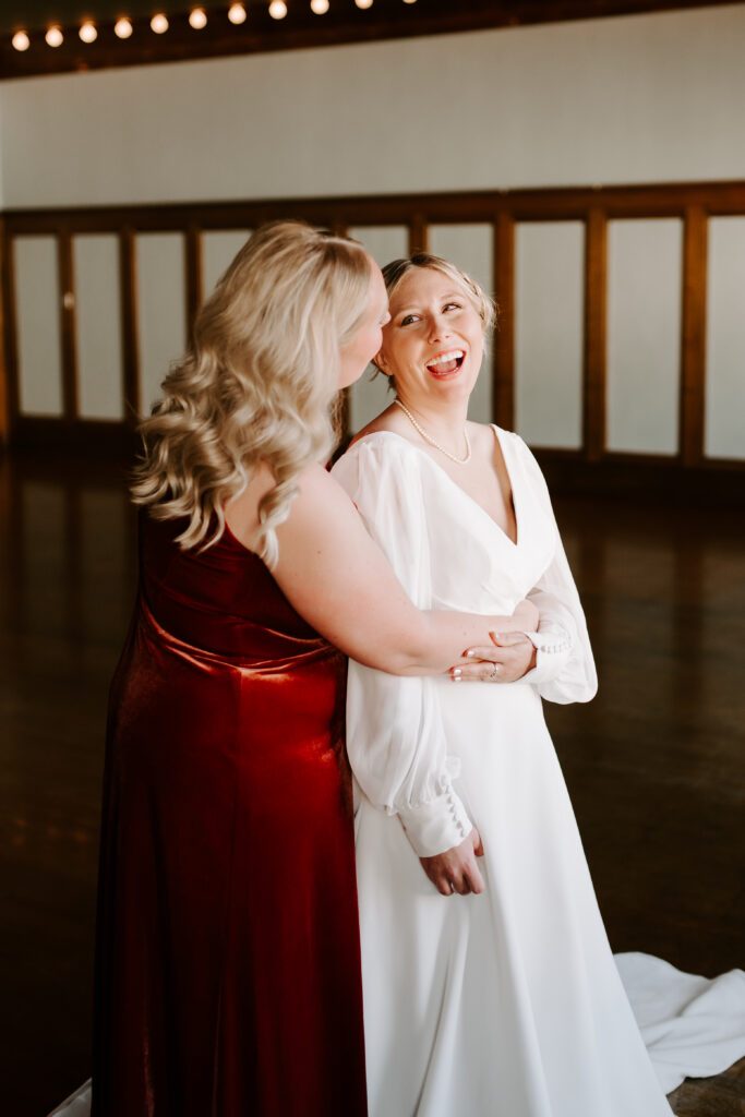 bride and maid of honor sister sharing a moment on wedding day