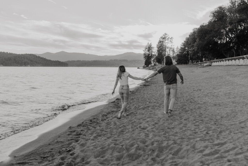 Couple walking together holding hands on the beach at Lake Coeur D'Alene