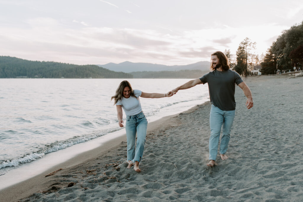 Couple walking together holding hands on the beach at Lake Coeur D'Alene