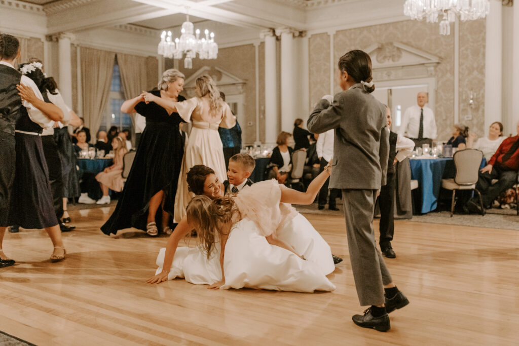 Bride getting tackled by kids during wedding reception