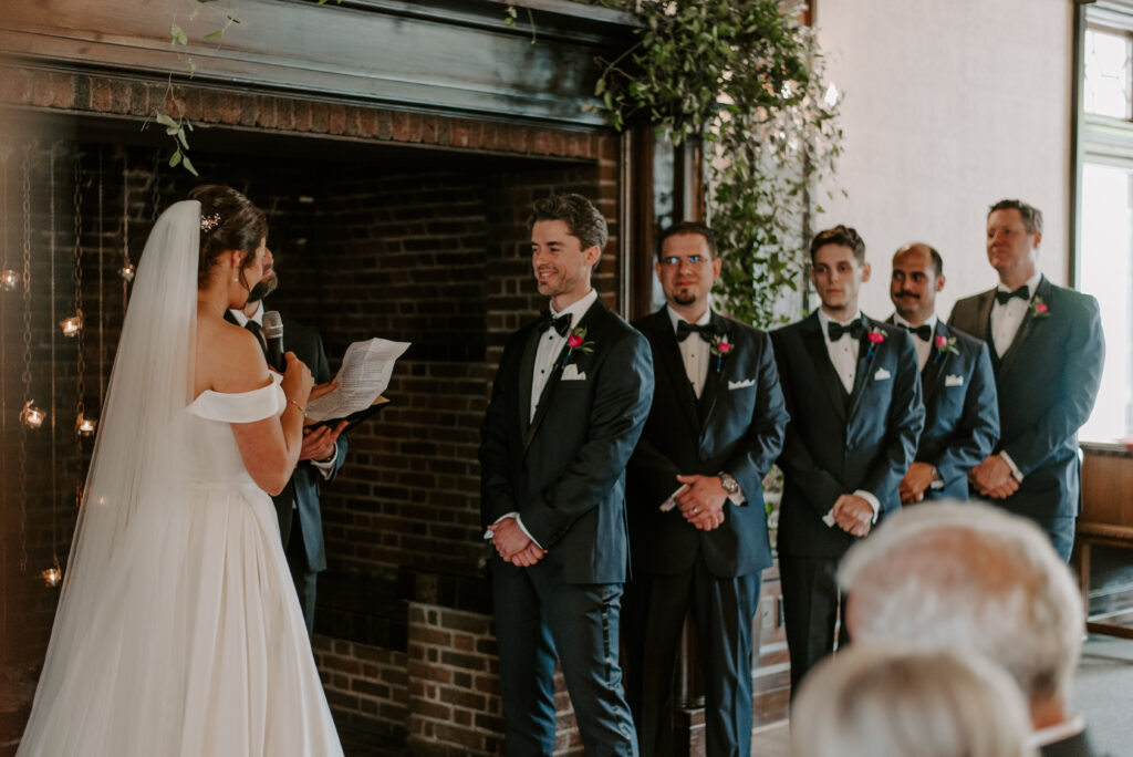 Groom smiling during bride's wedding vows