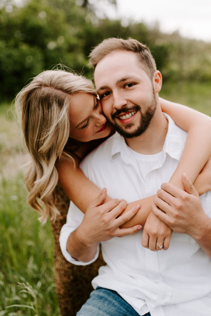 future groom smiling at the camera with future bride