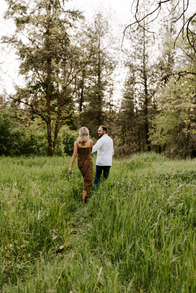 future bride and groom walking together through the meadow