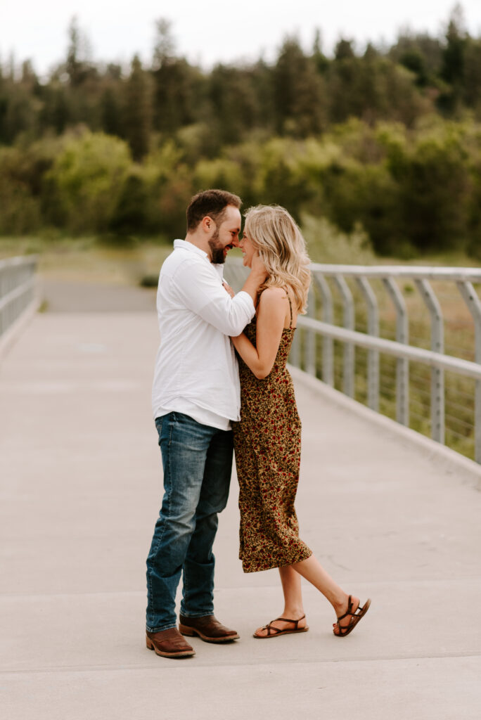 future bride and groom standing on bridge going in for a kiss