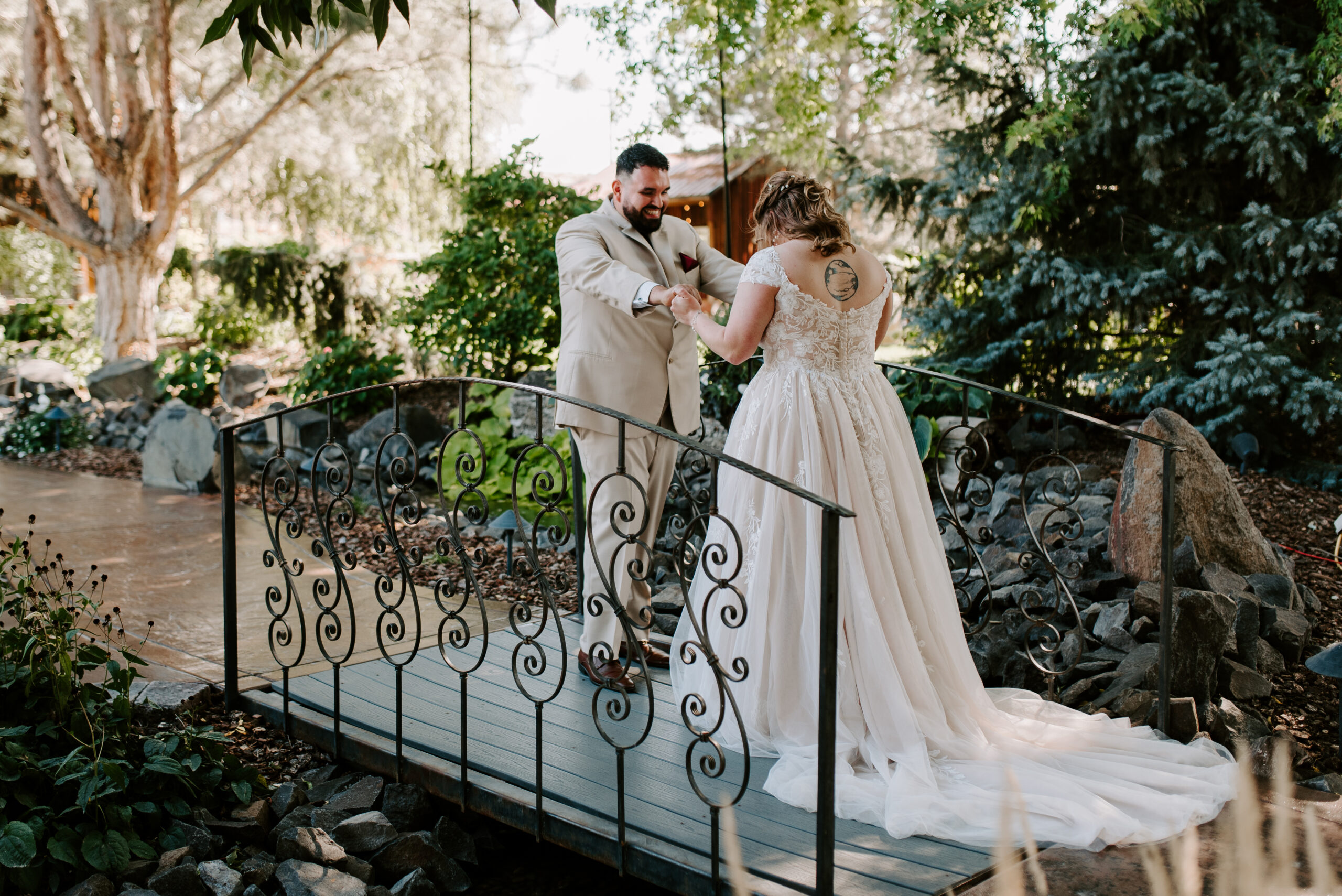 A couple getting married has a first look on their wedding day, and the groom holds the bride's hands out to look at her whole dress.