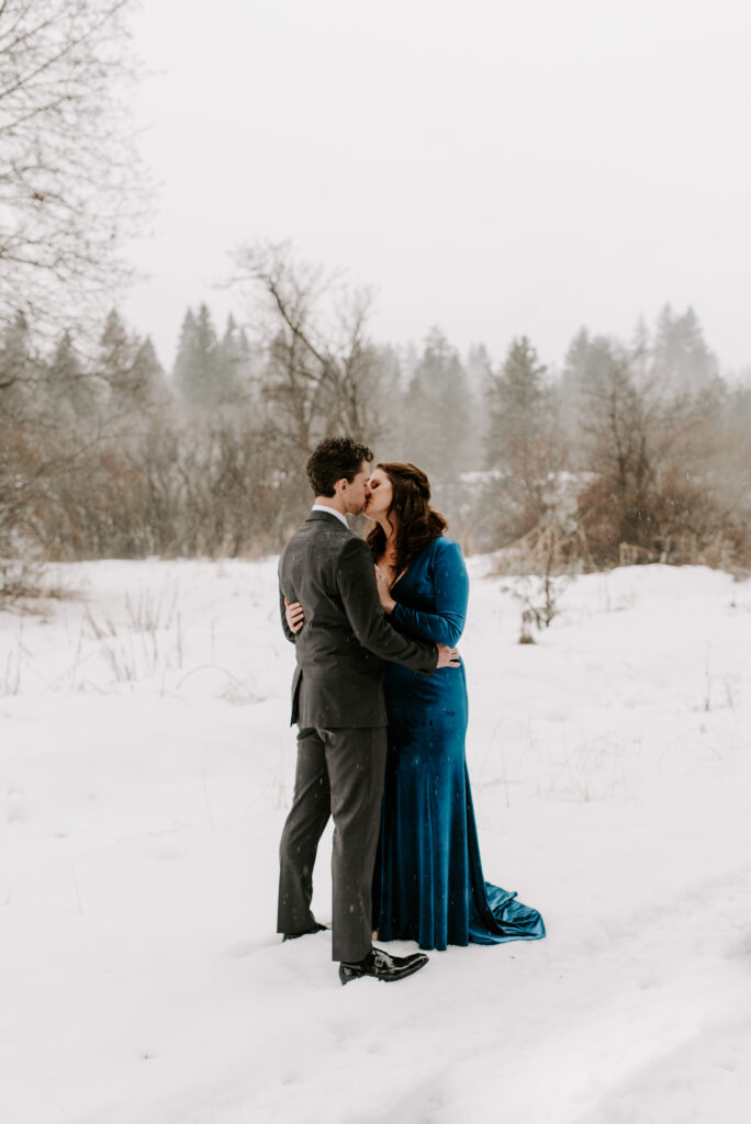 An engaged couple taking winter photos in the snow.